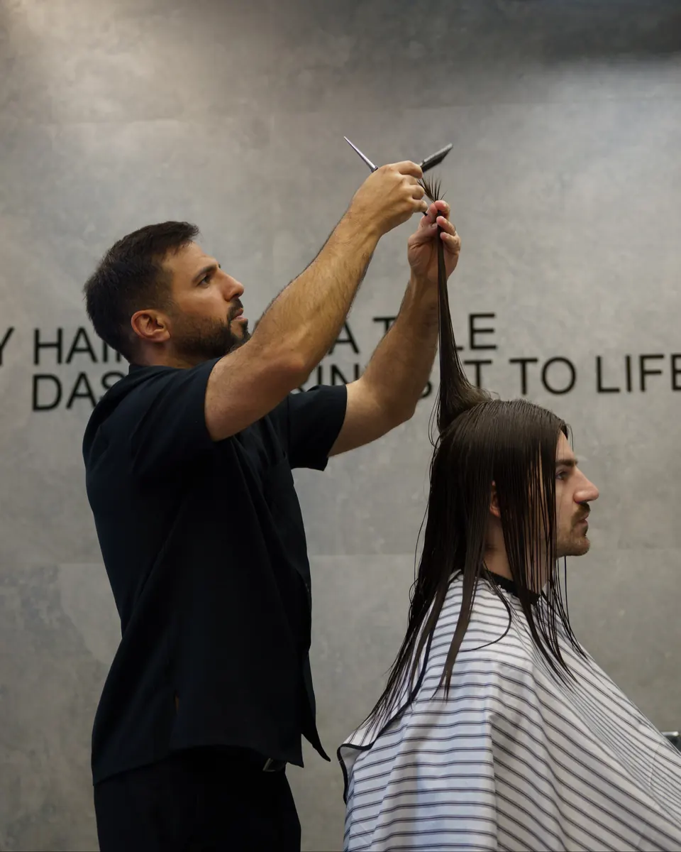 Sam lifting a section of long hair to cut it