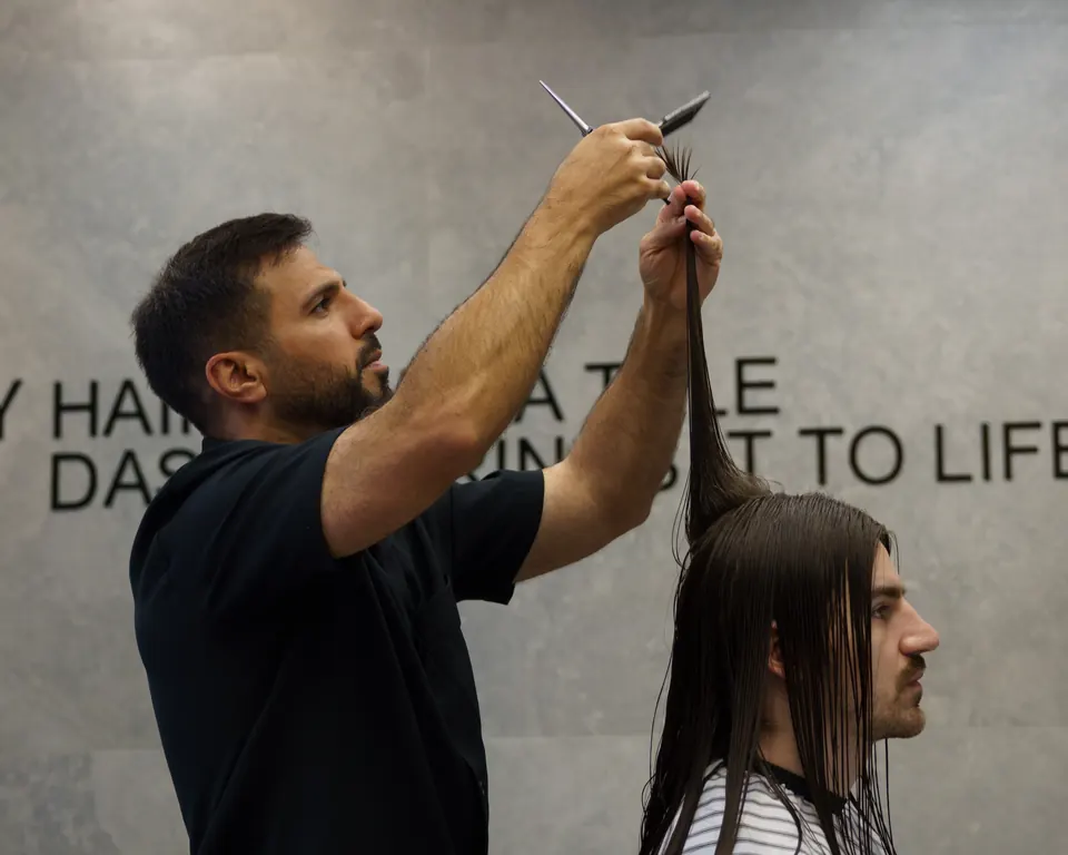 Sam lifting a section of long hair to cut it