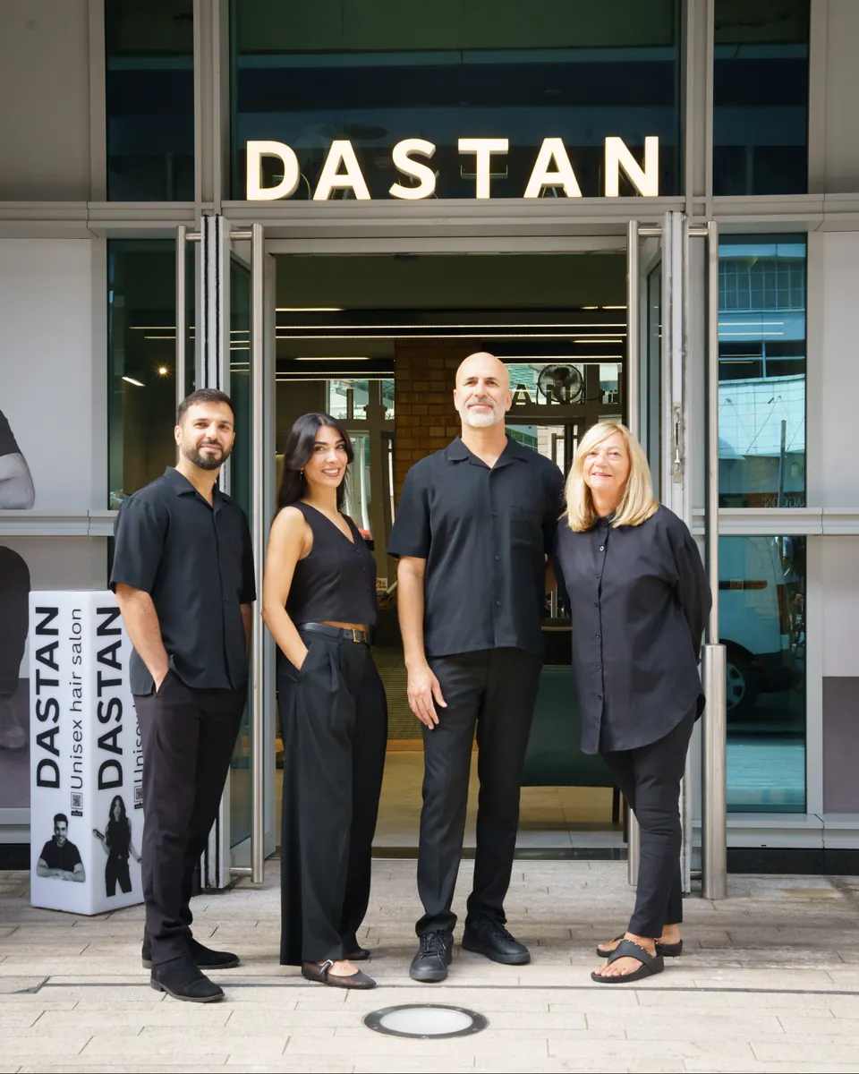 Four of the team at the open doors under the Dastan sign
